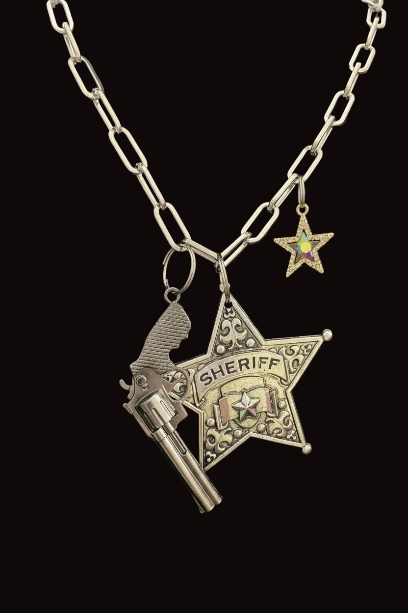 Silver sheriff's star pendant with gun silhouette on a chain against a black background