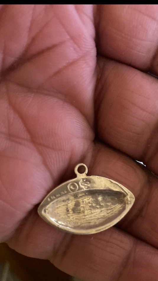 Sterling Silver pendant held between fingers against a blurred background