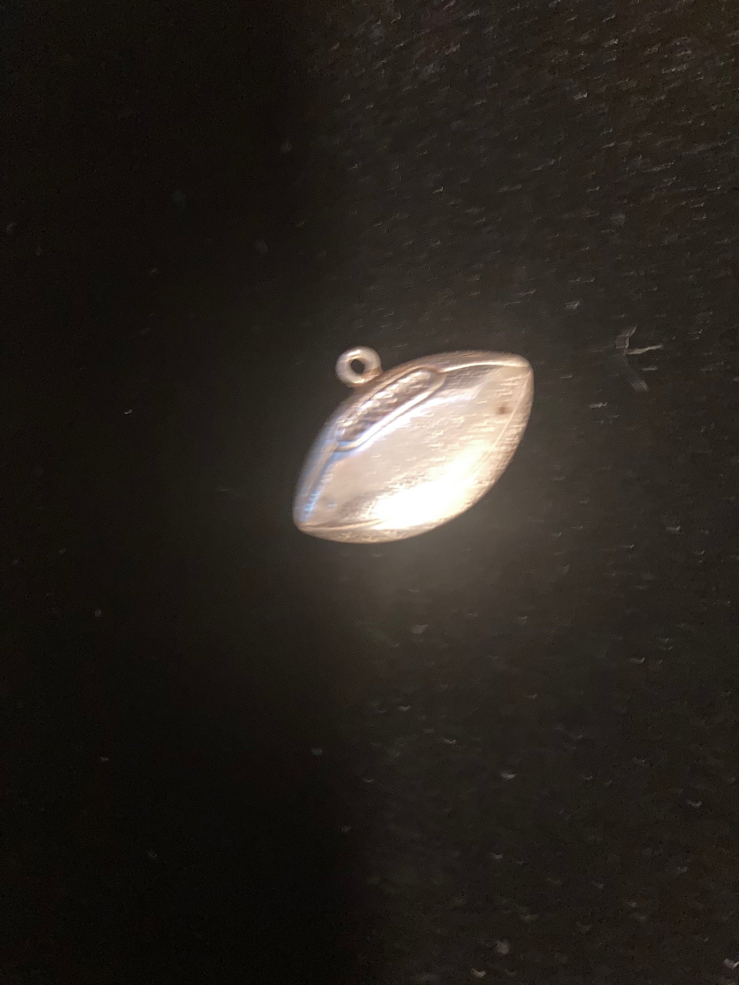 Silver pendant/charm on a dark background
