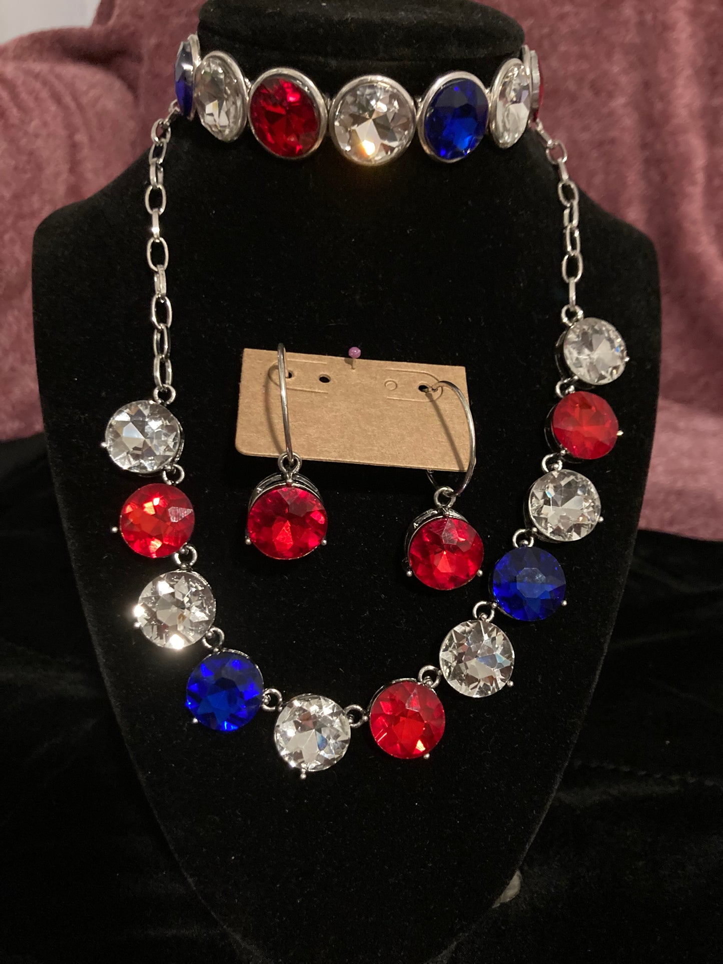 Necklace with red, blue, and clear gemstones on a black stand
