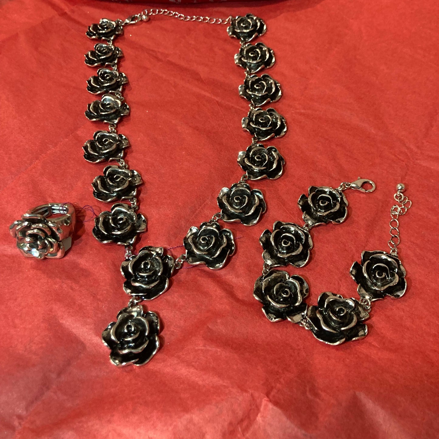 Silver rose-shaped necklace on a red fabric background