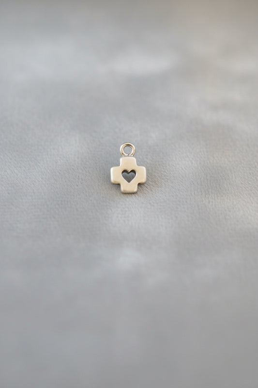 Small gold cross charm with a heart on a black background