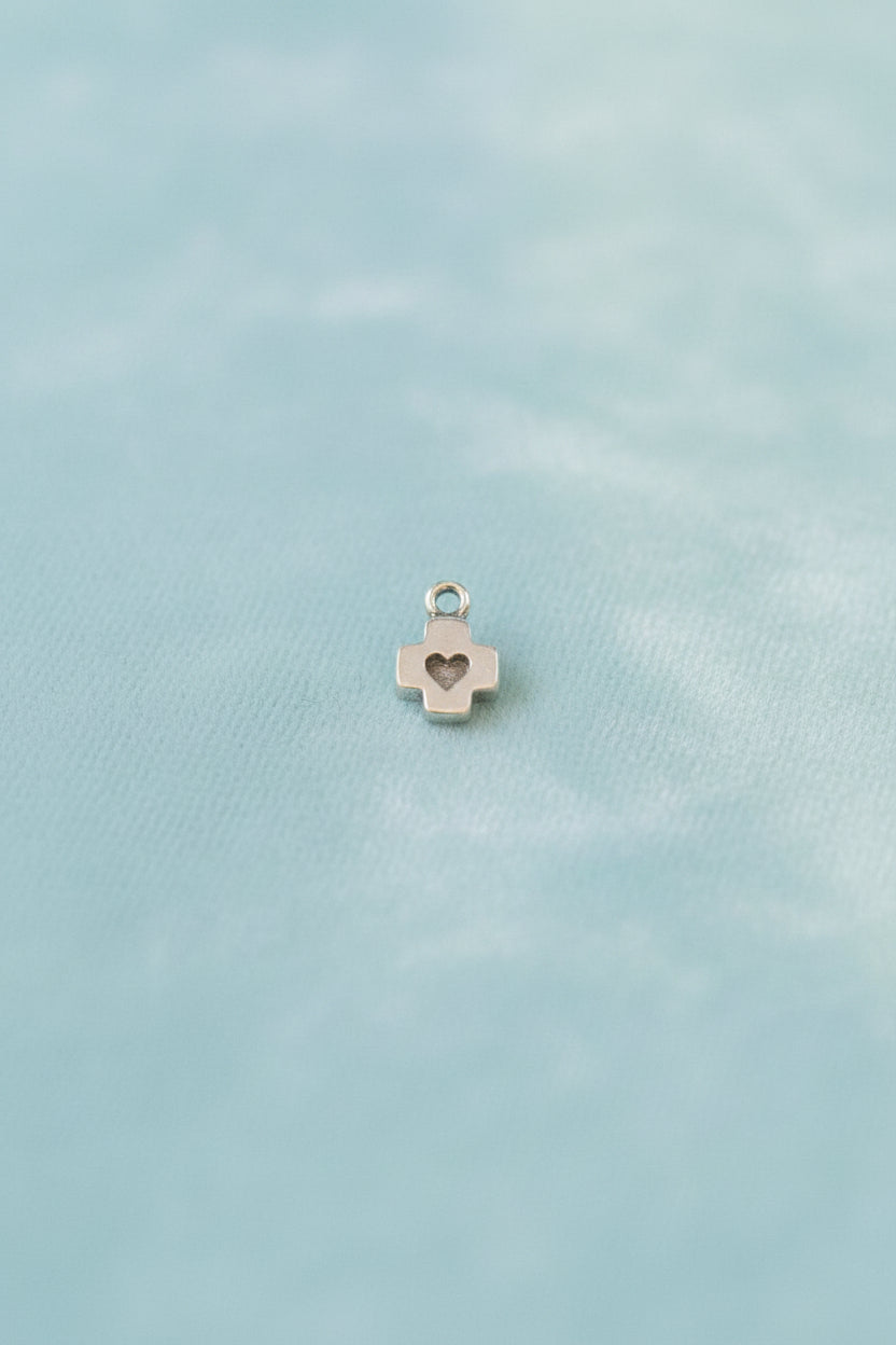Small cross-shaped pendant with a heart in the center on a blue background