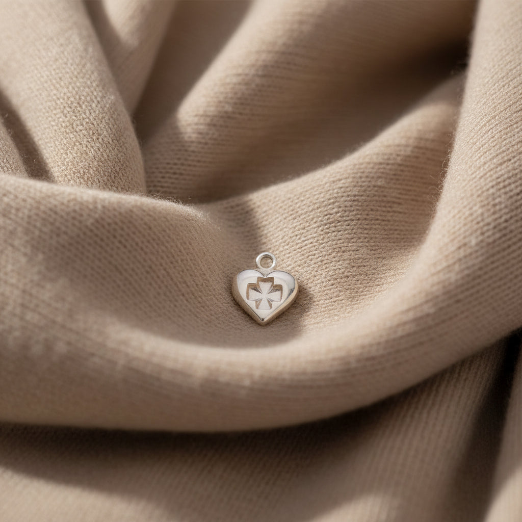 Heart-shaped charm with a cross design on a black background